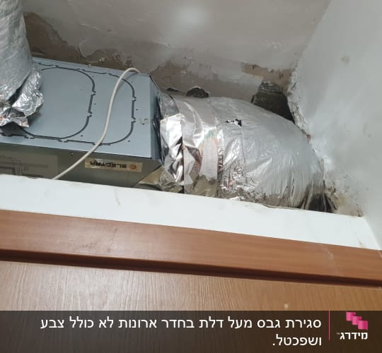 צינור מיזוג מכוסה בנייר כסף ליד קיר גבס